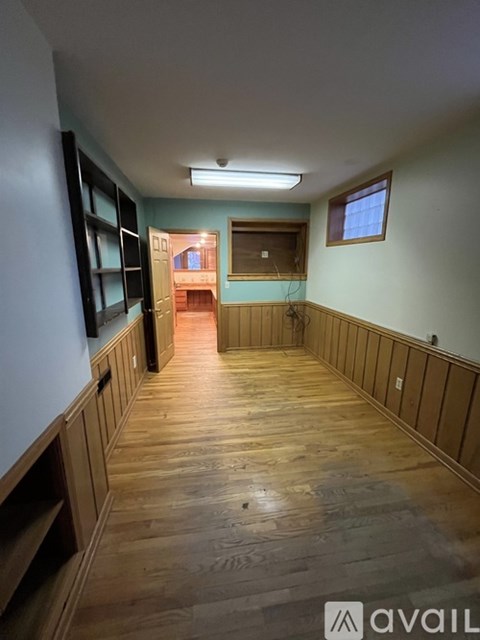 A long hallway with wooden floors and a window.