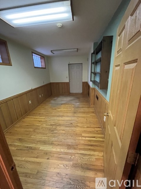 A long hallway with wooden floors and doors on both sides.