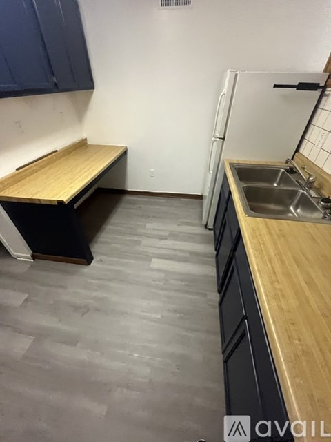A kitchen with a wooden counter and a white fridge.