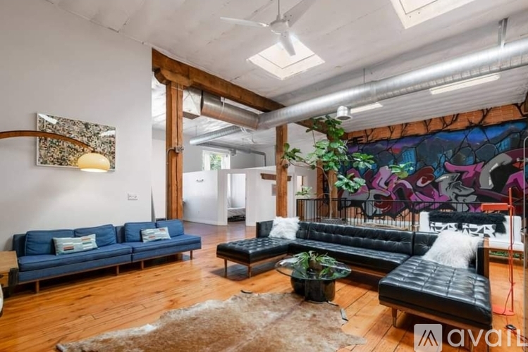 A living room with a blue couch and a black leather couch.