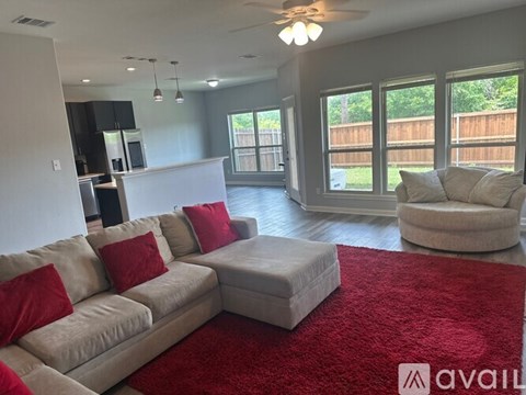 A living room with a white couch and red pillows.