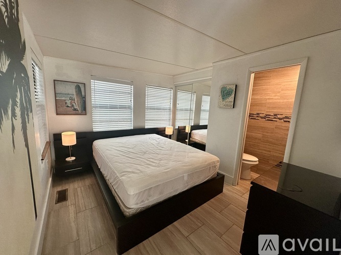 A bedroom with a large bed and a painting on the wall.
