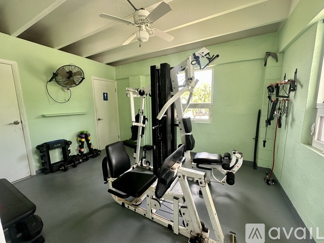 A home gym with a variety of equipment including a weight bench, a fan, and a window.