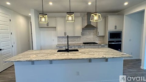 A kitchen with a granite countertop and pendant lights.