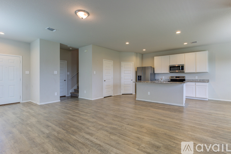 A spacious living room with a kitchen area in the background.