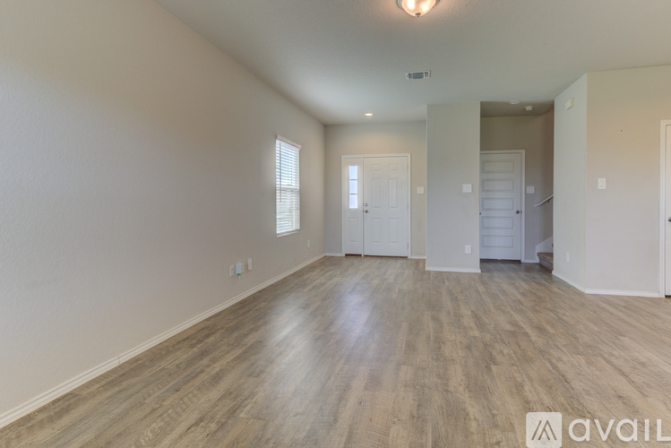 A spacious room with wooden flooring and white walls.