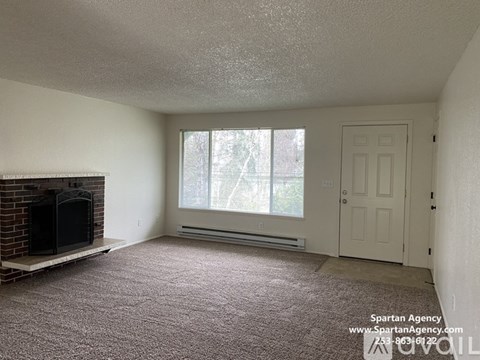 A Spartan Agency image of a carpeted room with a fireplace and a door.