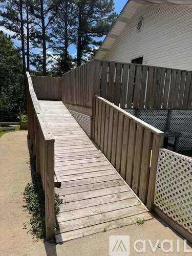 A wooden staircase with a metal railing leads up to a house.