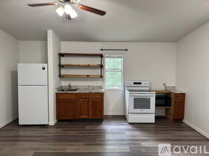 A kitchen with a white fridge, a white oven, and wooden cabinets.