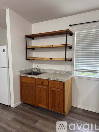 A kitchen with a white fridge, wooden cabinets, and a marble countertop.