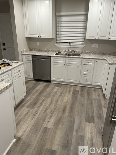 A kitchen with white cabinets and a wooden floor.