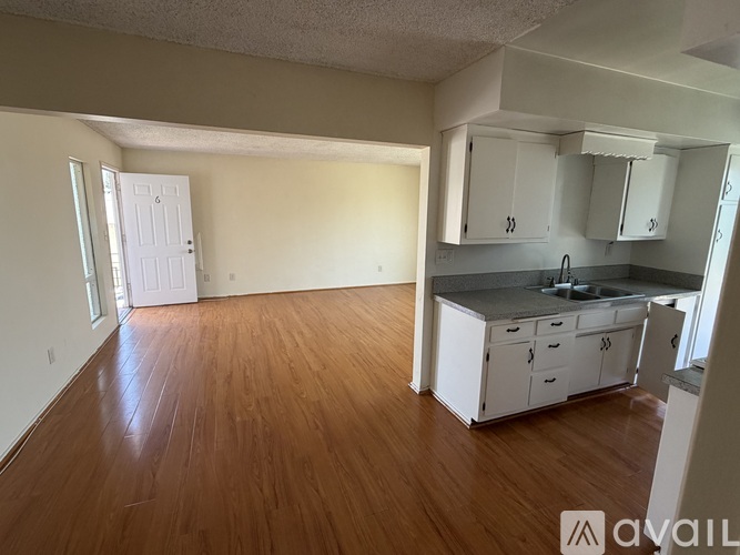 A kitchen with white cabinets and a wooden floor.