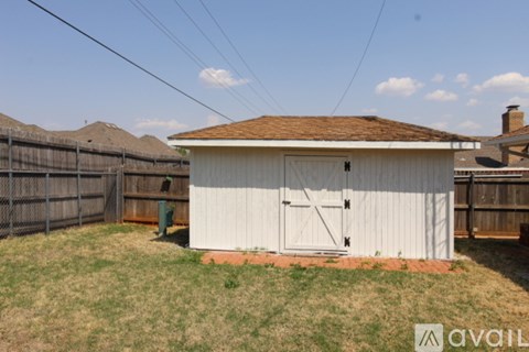 A small white shed with a brown roof is situated in a grassy area.