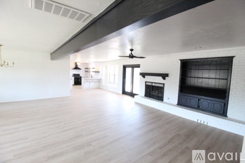 A spacious living room with a fireplace and a ceiling fan.