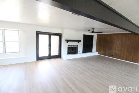 A spacious room with a fireplace and a ceiling fan.