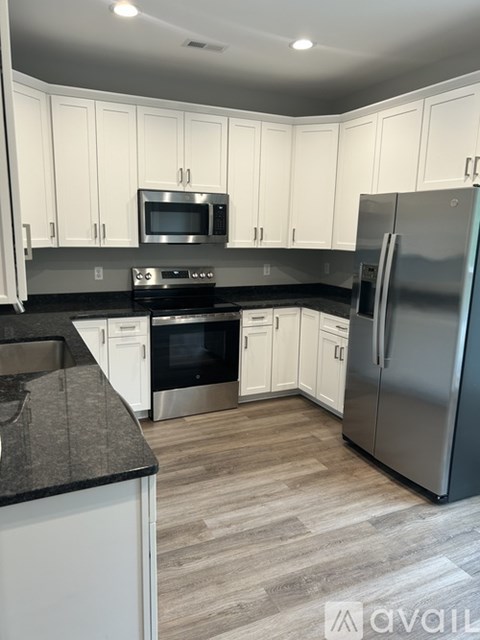 A kitchen with white cabinets and a black countertop.