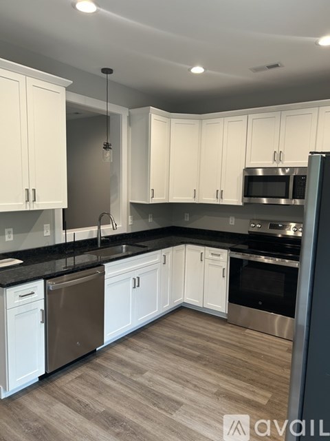 A kitchen with white cabinets and a black countertop.