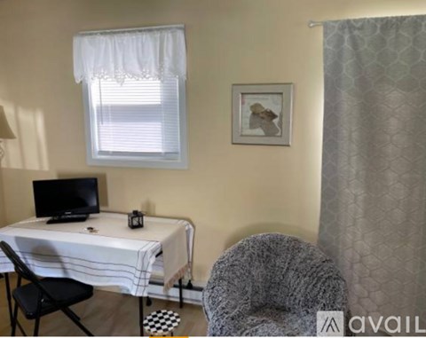 A small room with a bed, chair, and a window with blinds.