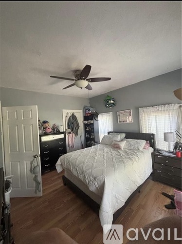A bedroom with a bed, dresser, and ceiling fan.