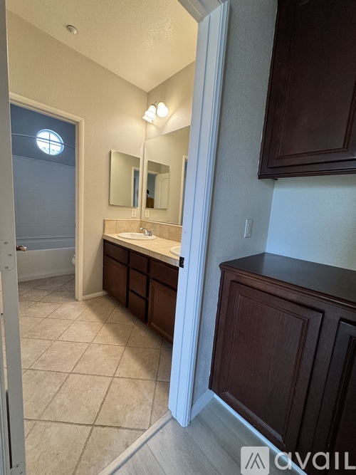A bathroom with a sink, mirror, and brown cabinetry.