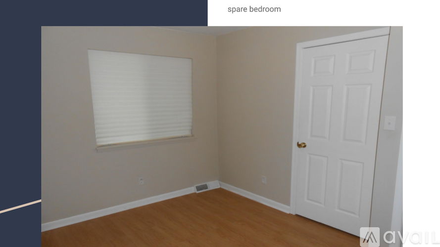 A spare bedroom with a white door and a window with blinds.
