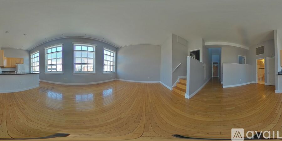 A spacious room with wooden floors and a curved wall.