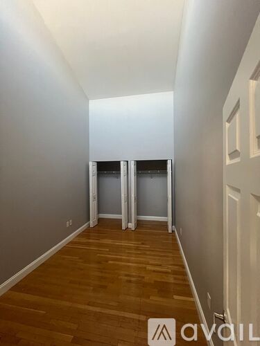 A hallway with wooden floors and white walls leading to a door.