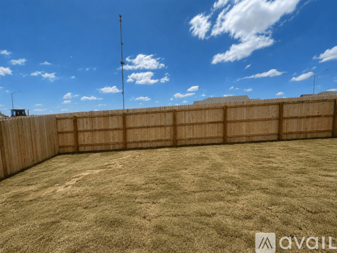 A backyard with a wooden fence and a grassy field.