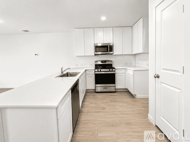 A white kitchen with wooden floors and white cabinets.