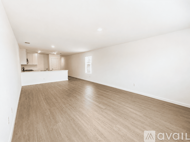 A spacious room with wooden flooring and white walls.