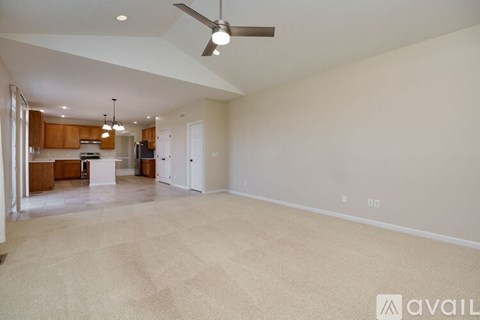 A spacious living room with a kitchen in the background and a carpet on the floor.