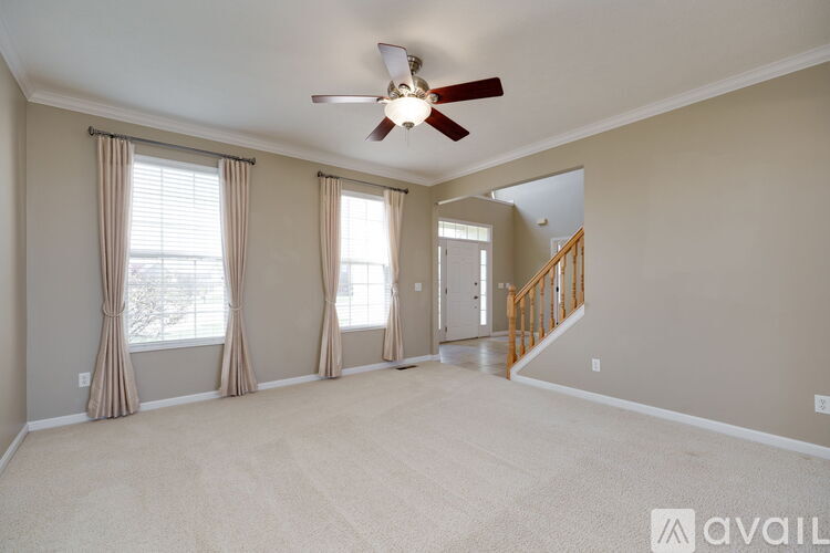 A spacious room with a ceiling fan and carpeted floor.