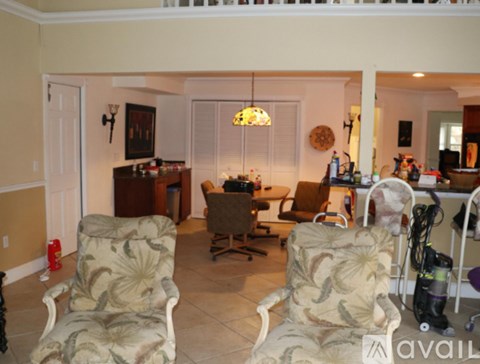 A living room with a couch, chairs, and a vacuum cleaner.