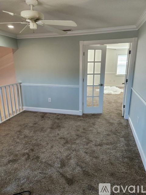A room with a carpeted floor and a ceiling fan.