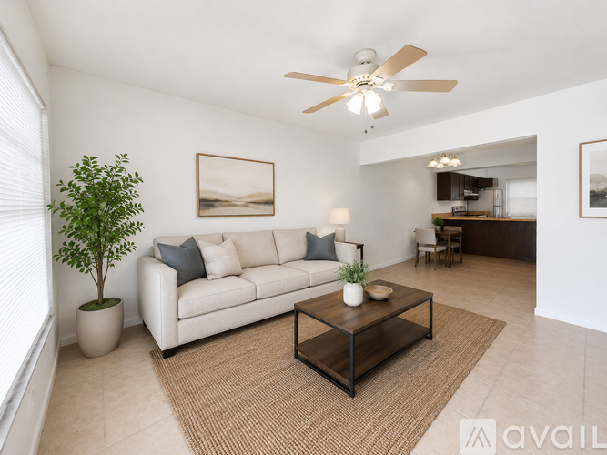 A living room with a white couch, a plant, a coffee table, and a ceiling fan.