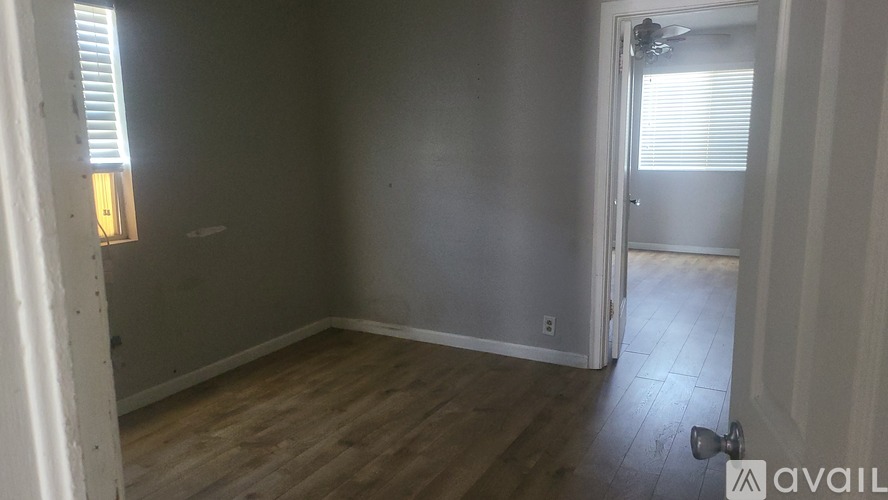 A room with wooden flooring and a door leading to another room.