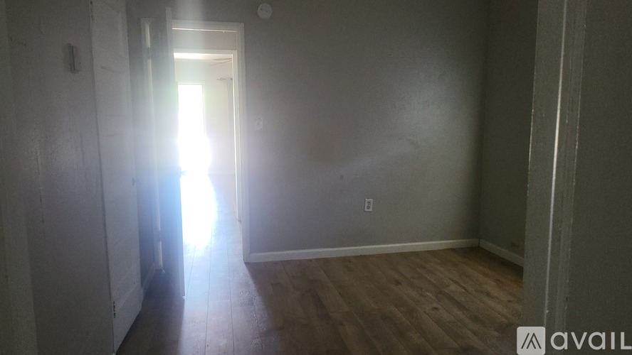 A room with a wooden floor and a doorway leading to another room.