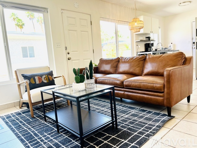 A living room with a brown leather couch and a glass coffee table.