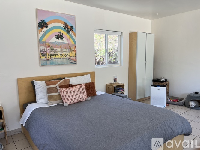 A bedroom with a large bed and a painting of a rainbow above it.