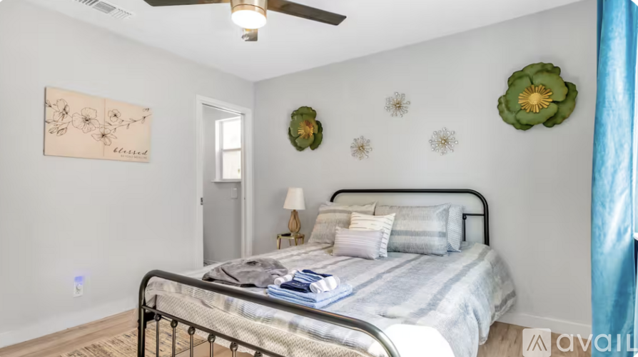 A bedroom with a bed, lamp, and wall decorations.