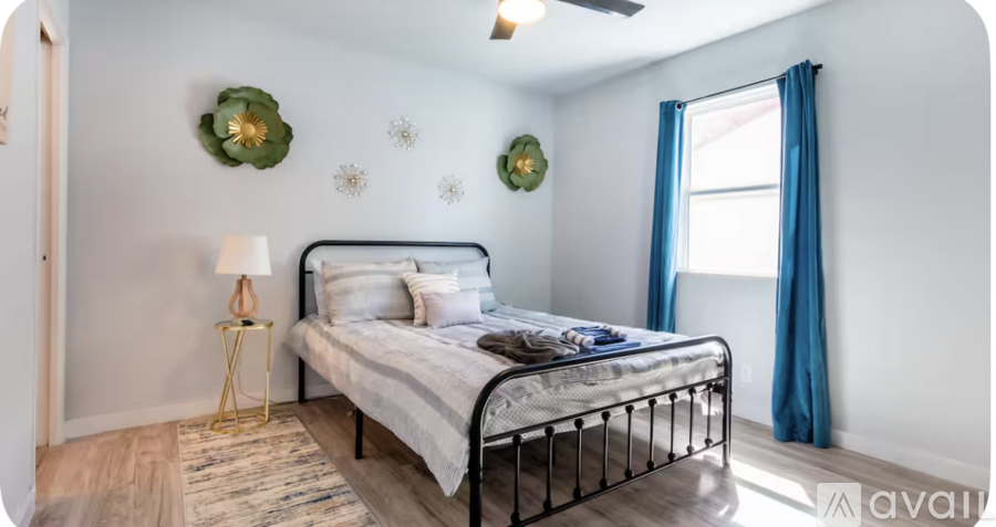 A bedroom with a bed, a lamp, and wall decorations.