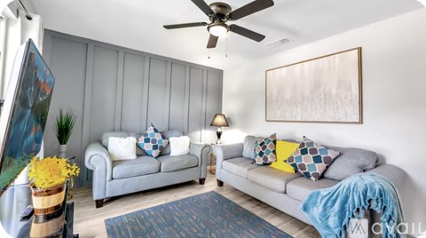 A living room with a grey couch, a blue blanket, and a painting on the wall.