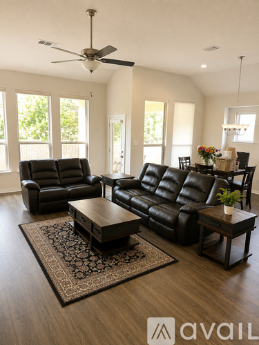 A living room with black leather furniture and a ceiling fan.