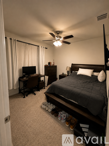 A bedroom with a bed, desk, and television.