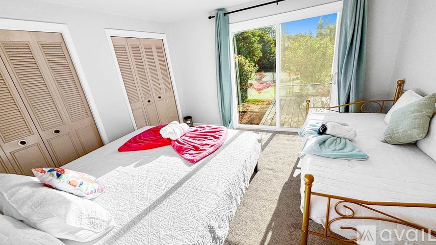 A bedroom with a large bed and a view of a garden outside the window.