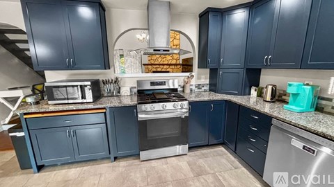 A kitchen with blue cabinets and a stove top oven.