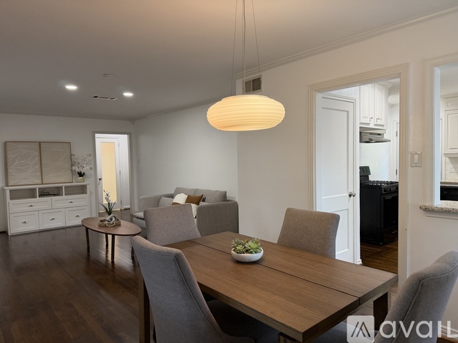 A modern dining room with a wooden table and grey chairs.