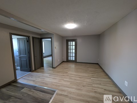 A spacious room with wooden flooring and a large window.
