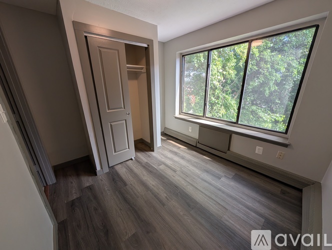 A room with a wooden floor and a window overlooking trees.