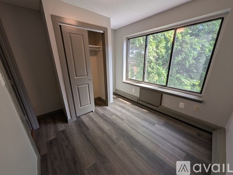 A room with a wooden floor and a window overlooking trees.